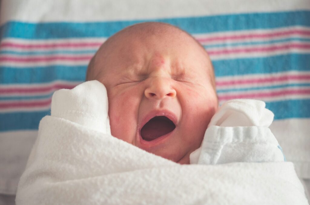Photo of yawning newborn on his hospital blanket by Tim Bish on Unsplash.